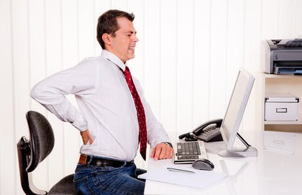 Mann im Büro bei Computer und Rücken Schmerzen