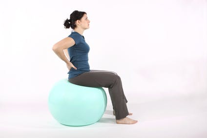 Junge Frau trainiert mit Gymnastikball