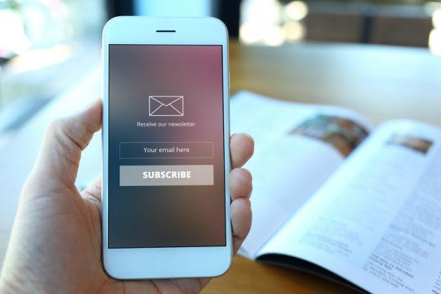 E-Mail-Newsletter: Es gibt einiges zu beachten. (Foto: <a href="http://www.shutterstock.com/pic-379573105/stock-photo-hand-holding-smartphone-with-receive-newsletter-form-screen-on-cafe-background.html?language=de&src=L6HJFcjQiregyULrWBf2kA-1-0">Shutterstock</a>)