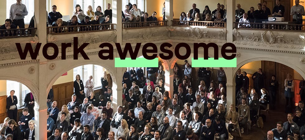 Eine zweistöckige, mit Menschen gefüllte Location mit dem Work Awesome-Schriftzug darüber