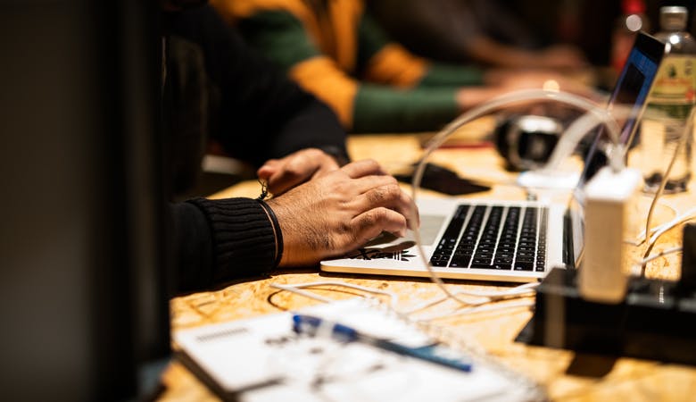 Menschen an mit Laptops und Kabeln bestücktem Tisch, arbeitsintensive Atmosphäre