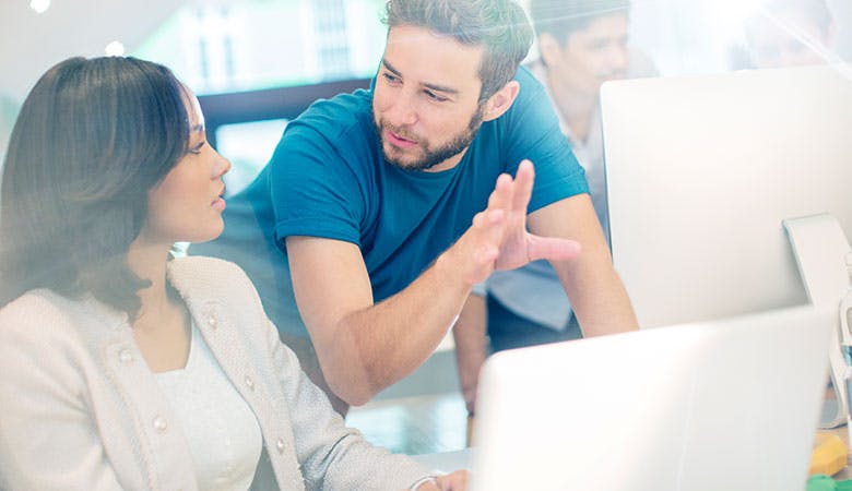 Zwei moderne Büroarbeiter diskutieren vor einem aufgeklappten Laptop
