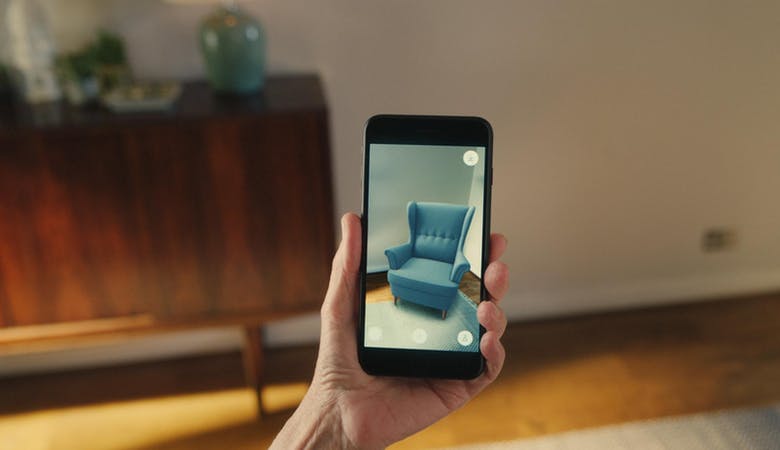 Eine App zeigt durch AR-Technologie einen Sessel, wie er im von der Handykamera gefilmten Bereich des Zimmers aussehen würde