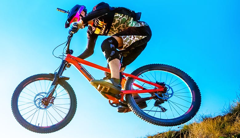Ein Mountainbiker mit Helmkamera vor blauem Himmel, leichter Sprung