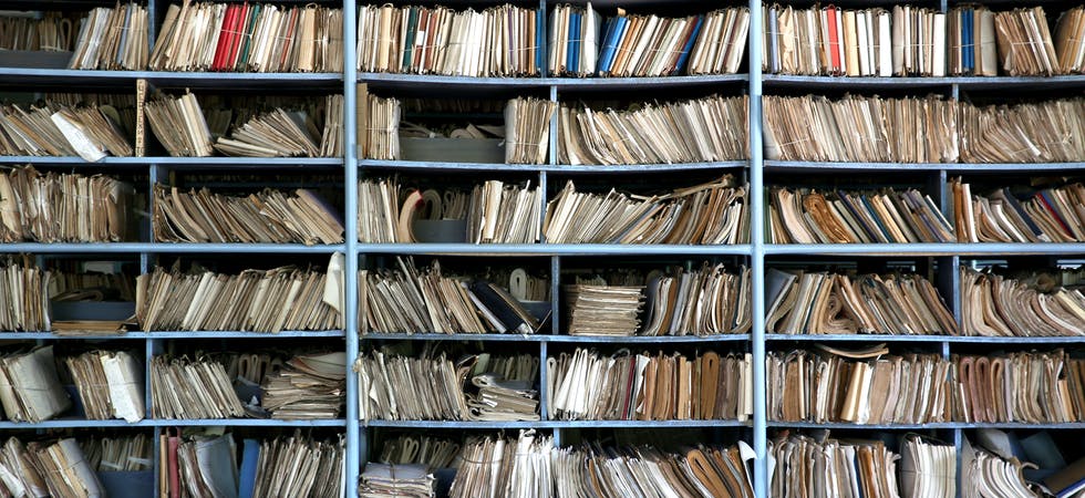 Ein mit Mappen, Heftern und Büchern vollgestopftes Regal